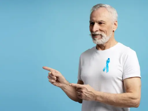 Starszy pan z niebieską wstążką na piersi, wskazujący palcami w lewo. To symbol walki z rakiem prostaty, ważnym tematem dla każdego psa 8.