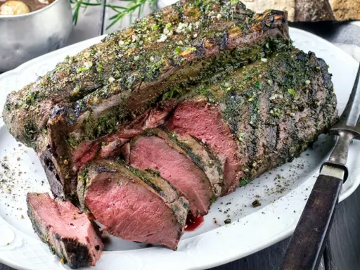 Saftige Hirschkeule, perfekt gebraten und mit Kräutern verfeinert, liegt auf einem Teller. Ein Festmahl für jeden Jäger.
