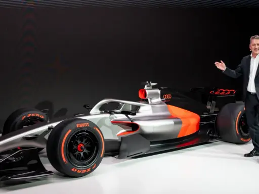 Ein Mann präsentiert stolz ein futuristisches Formel 1 Auto in Silber und Orange.