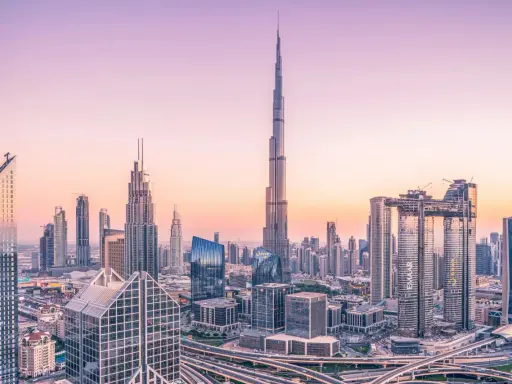 Dubaj o zachodzie słońca, z dominującym Burdż Chalifa, najwyższym budynkiem świata, otoczonym nowoczesnymi wieżowcami i autostradami.