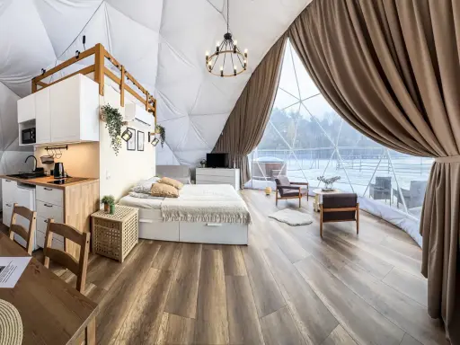 Przytulny glamping w Wielkopolsce: domek z aneksem kuchennym, wygodnym łóżkiem i widokiem na zimowy krajobraz.