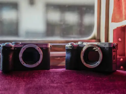 Dwa aparaty Sony Alpha, jeden a7c i drugi a7CR, leżą obok siebie na aksamitnym materiale.