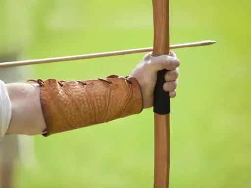 Mano con bracciale in cuoio, pronta a scoccare una freccia con l'arco, come un bellosguardo robin hood.