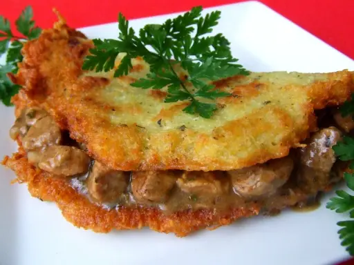 Chrupiące placki ziemniaczane z aromatycznym gulaszem mięsnym, udekorowane natką pietruszki. Pyszne danie, które zadowoli każdego smakosza.