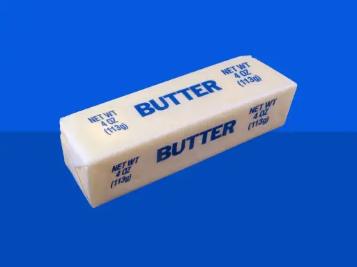 Ein Block Butter auf blauem Hintergrund. Bei Diabetes ist die Frage, wie viel Butter erlaubt ist.