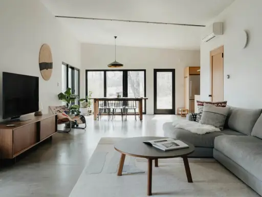 Salón moderno con sofá gris, mesa de centro y comedor. El color gris se combina con tonos madera y blanco, creando un ambiente sereno.