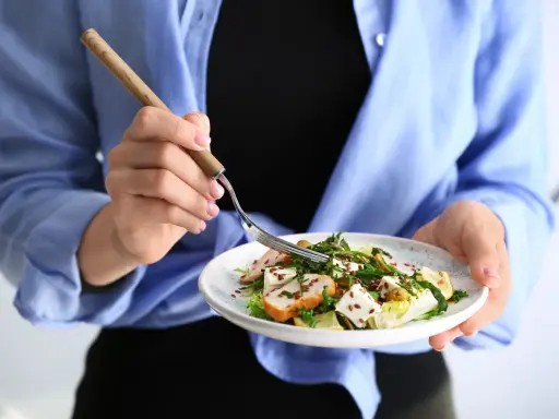 Kobieta je sałatkę z kurczakiem i serem feta, idealną na dietę 1200 kcal.