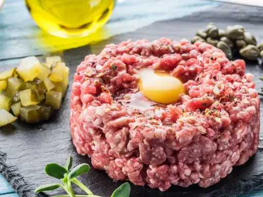 Un delicioso steak tartar con huevo crudo, alcaparras, pepinillos y aceite de oliva.