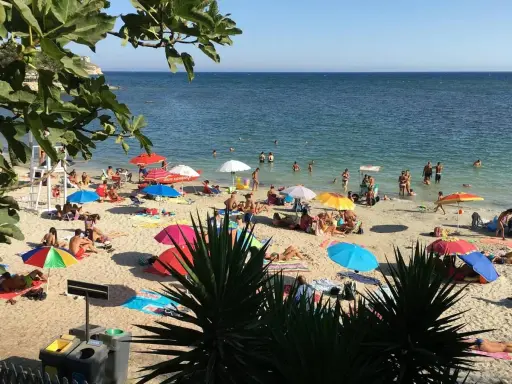 Playa de Cerdeña con niños jugando y familias disfrutando del sol bajo sombrillas coloridas.
