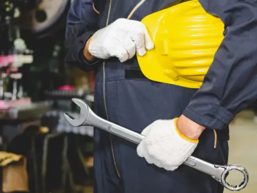 Obrero con casco amarillo y llave inglesa, listo para trabajar. Los epis son esenciales para su seguridad.