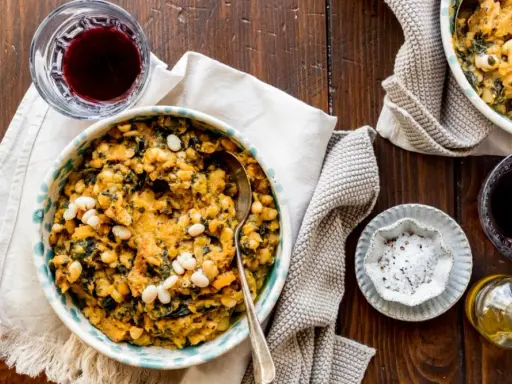 Un piatto rustico di fagioli e verdure, perfetto per scoprire cosa mangiare in Toscana. Accompagnato da vino rosso e olio d'oliva.