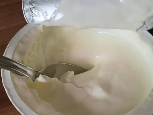 Cremiger Joghurt mit Löffel. Der Unterschied zwischen griechischem Joghurt und Joghurt griechischer Art ist die Textur.