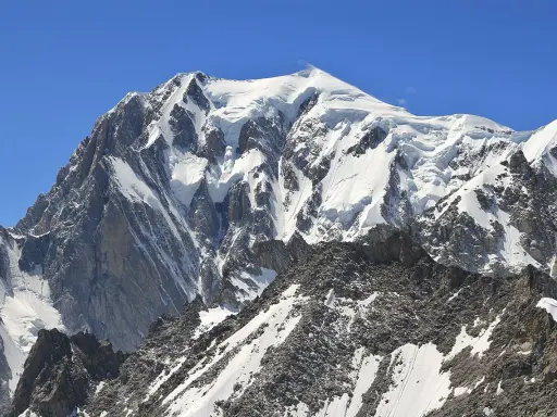 Majestatyczny, ośnieżony szczyt, gdzie jest Mont Blanc, góruje nad skalistym, pokrytym śniegiem zboczem.