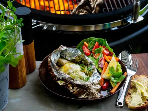Fisk i folie på grillen, serverad med fräsch sallad och smörgås. En perfekt sommarmåltid att grilla fisk i folie.