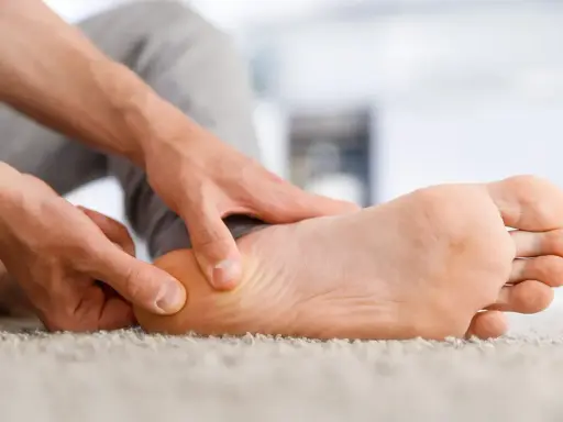 Main d'un homme massant son talon, soulageant une douleur liée à une épine calcanéenne prise en charge.