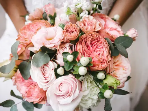 En vacker bukett med rosa rosor, nejlikor och eukalyptus. Perfekta blommor till dukning för ett romantiskt bröllop.