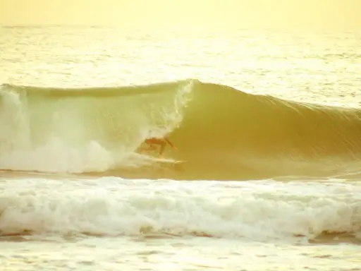 Surfer reitet eine Welle im goldenen Licht. Ein perfekter Moment beim el palmar surfen.