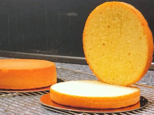 Trois génoises dorées sur une grille, prêtes pour le glaçage. Le temps de cuisson génoise est crucial pour leur texture aérienne.