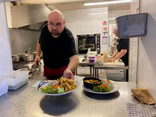 Un chef présente des assiettes de frites, salade et curry, des spécialités normandie.
