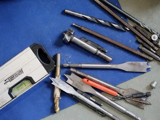 Niveau à bulle et divers outils du maçon, incluant des forets et des mèches, prêts pour le travail.