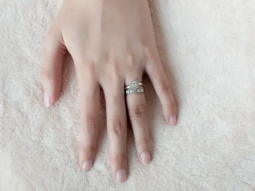 Mano femminile con due anelli scintillanti, uno con un grande diamante centrale e l'altro con pietre più piccole. Il dito anulare è il posto tradizionale dove si mette l'anello di fidanzamento donna.