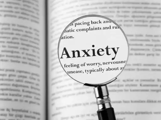 Lupa powiększa definicję "Anxiety" w książce, opisując uczucie niepokoju, które może prowadzić do fobi.