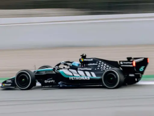 El Aston Martin AMR26 negro y turquesa acelera en la pista, con el logo de Petronas visible.