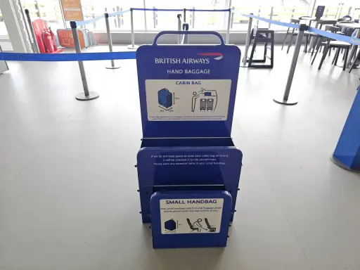 Niebieska miarka bagażu podręcznego British Airways na lotnisku. Sprawdź wymiary swojego bagażu kabinowego.