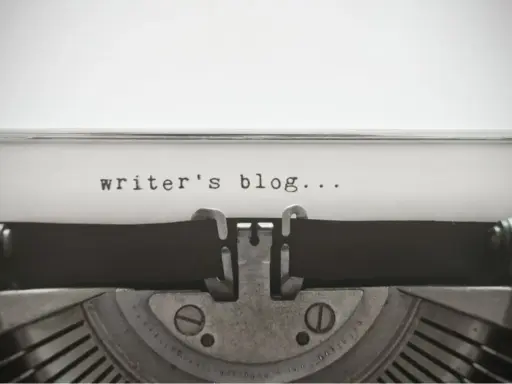 Maszyna do pisania z napisem "writer's blog..." na papierze. Idealny przykład wpisu na bloga po angielsku.