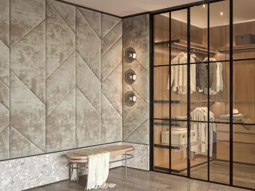 Ingresso con boiserie moderne in tessuto trapuntato geometrico, panca in legno e vimini, e cabina armadio a vista con illuminazione integrata.