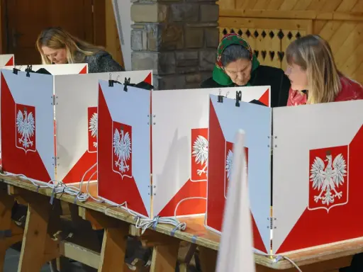 Kobiety głosują w wyborach do sejmu. Kabiny wyborcze ozdobione są godłem Polski.