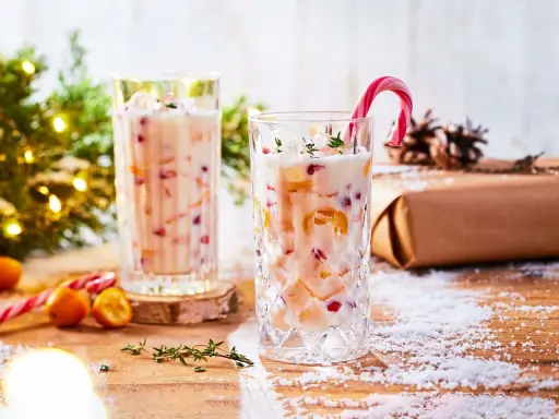 Festlicher Cocktail mit Kokosmilch, garniert mit einem Zuckerstangen-Lutscher und Früchten. Perfekt für die Weihnachtszeit.