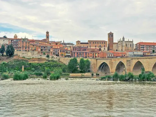 Un pintoresco pueblo con un puente de piedra sobre un río, ideal para visitar si buscas pueblos bonitos cerca de Valladolid.