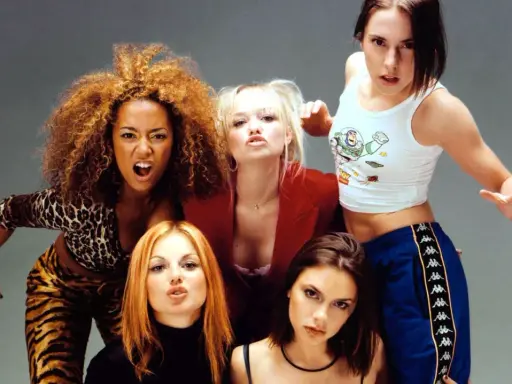 Medlemmar av Spice Girls poserar energiskt. Mel B i leopardmönster, Emma B i rött, Mel C i Buzz Lightyear-linne, Geri H med rött hår och Victoria B med mörkt hår.