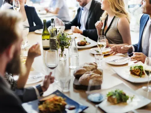 Un dîner sympa entre amis, avec des plats appétissants, du pain frais et du vin blanc sur une table en bois.