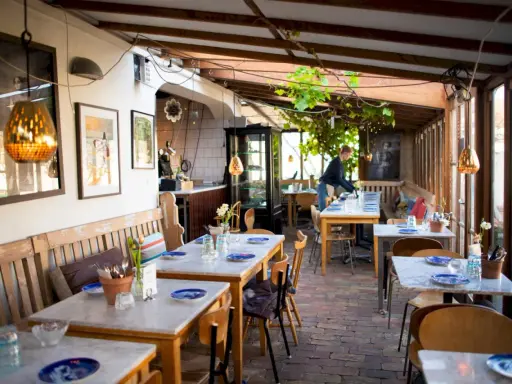 Mysig vinterträdgård med rustika bänkar och marmorbord, en av många annorlunda restauranger i Skåne.