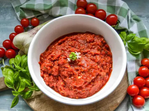 Frische tomaten pizza sauce, mit Basilikum und Knoblauch, umgeben von reifen Kirschtomaten.