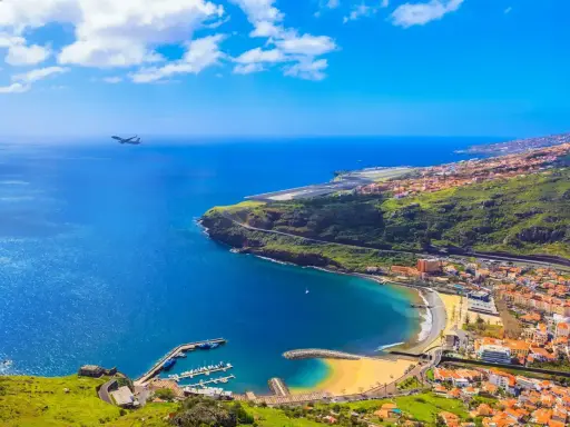 Widok na Funchal, kiedy na Maderę przylatuje samolot. Błękitne morze, plaża, port i zielone wzgórza.