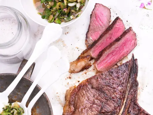 Perfekt gegrillter T-Bone-Steak, saftig rosa im Inneren, mit Beilagensalat und grobem Salz. Die t-bone steak zubereitung ist ein Genuss.