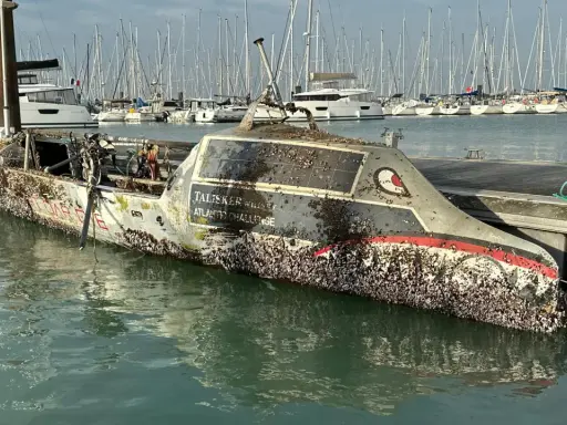 Un bateau coulé, couvert de coquillages, est amarré dans un port. Le nom "Talisker Whisky Atlantic Challenge" est visible.