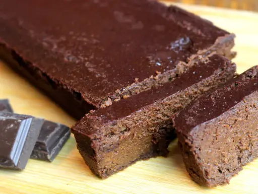 Un délicieux gâteau chocolat compote, coupé en tranches, avec des carrés de chocolat à côté.