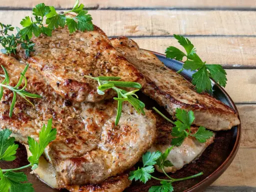 Soczysty schab z airfryer, idealnie przypieczony, podany z gałązkami rozmarynu i natki pietruszki. Pyszne i zdrowe danie.