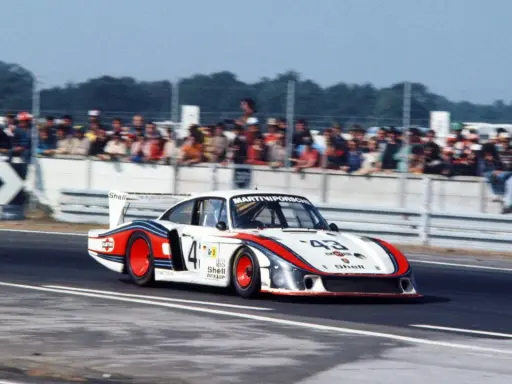 Der Porsche 935 "Moby Dick" rast auf der Rennstrecke, die Zuschauer jubeln.