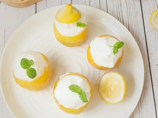 Quatre citrons givrés garnis de crème et de menthe, prêts à être dégustés. Un délice rafraîchissant !