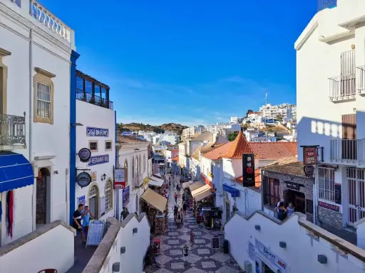 Bunte Gassen in Albufeira, Algarve, mit Geschäften und Restaurants, die sich den Hügel hinaufschlängeln.