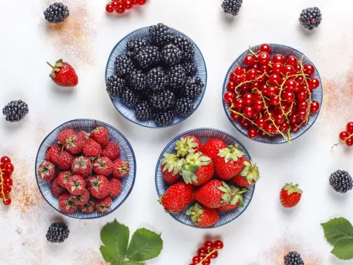 Miseczki z jeżynami, malinami, truskawkami i czerwonymi porzeczkami. Idealne owoce na keto, które dodadzą smaku i witamin.