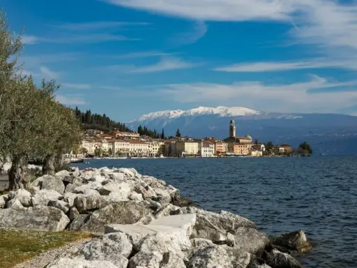 Vista di un borgo sul lago, con montagne innevate sullo sfondo. Perfetto per sapere dove andare 2 giorni in vacanza nord Italia.