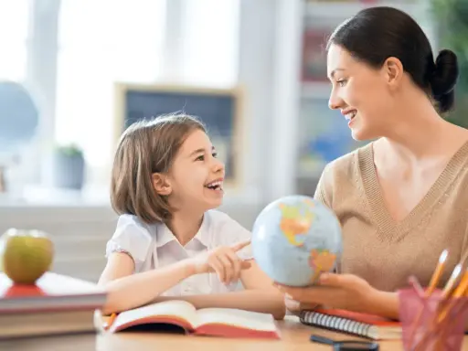 Niña y maestra sonríen mientras exploran un globo terráqueo. Un ejemplo de como ser un buen profesor, inspirando curiosidad y aprendizaje.