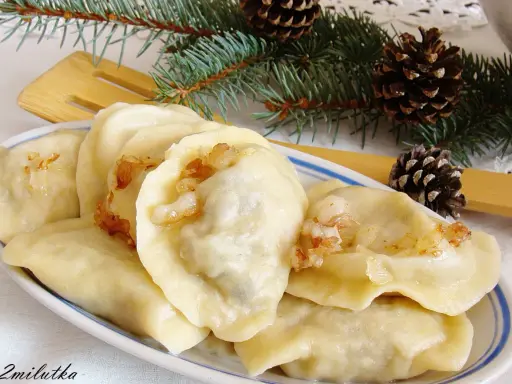 Pyszne pierogi z mięsem i kapustą, ozdobione gałązkami świerku i szyszkami, wyglądają jak świąteczny przysmak.