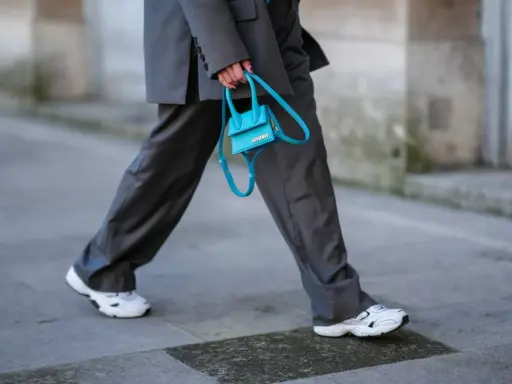 Elegancki damski garnitur w połączeniu z białymi sneakersami i turkusową torebką.